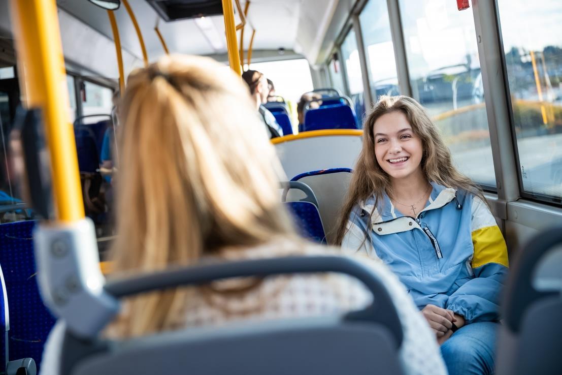 Ung passasjer på buss som smiler og er blid - Klikk for stort bilete
